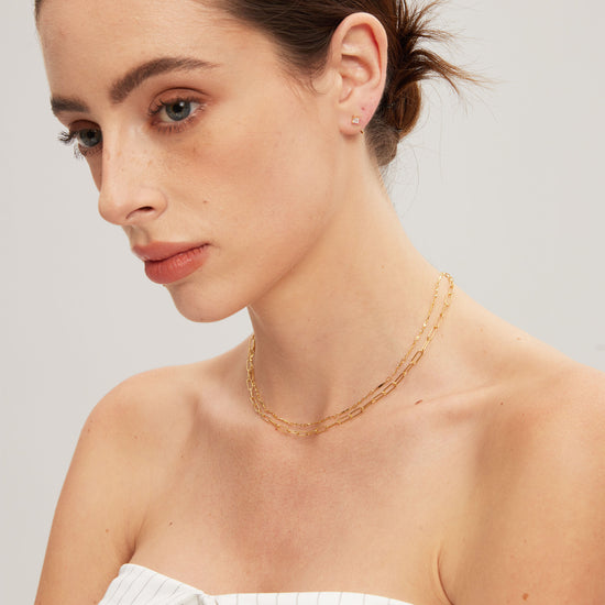 Woman wearing gold chains against a plain background