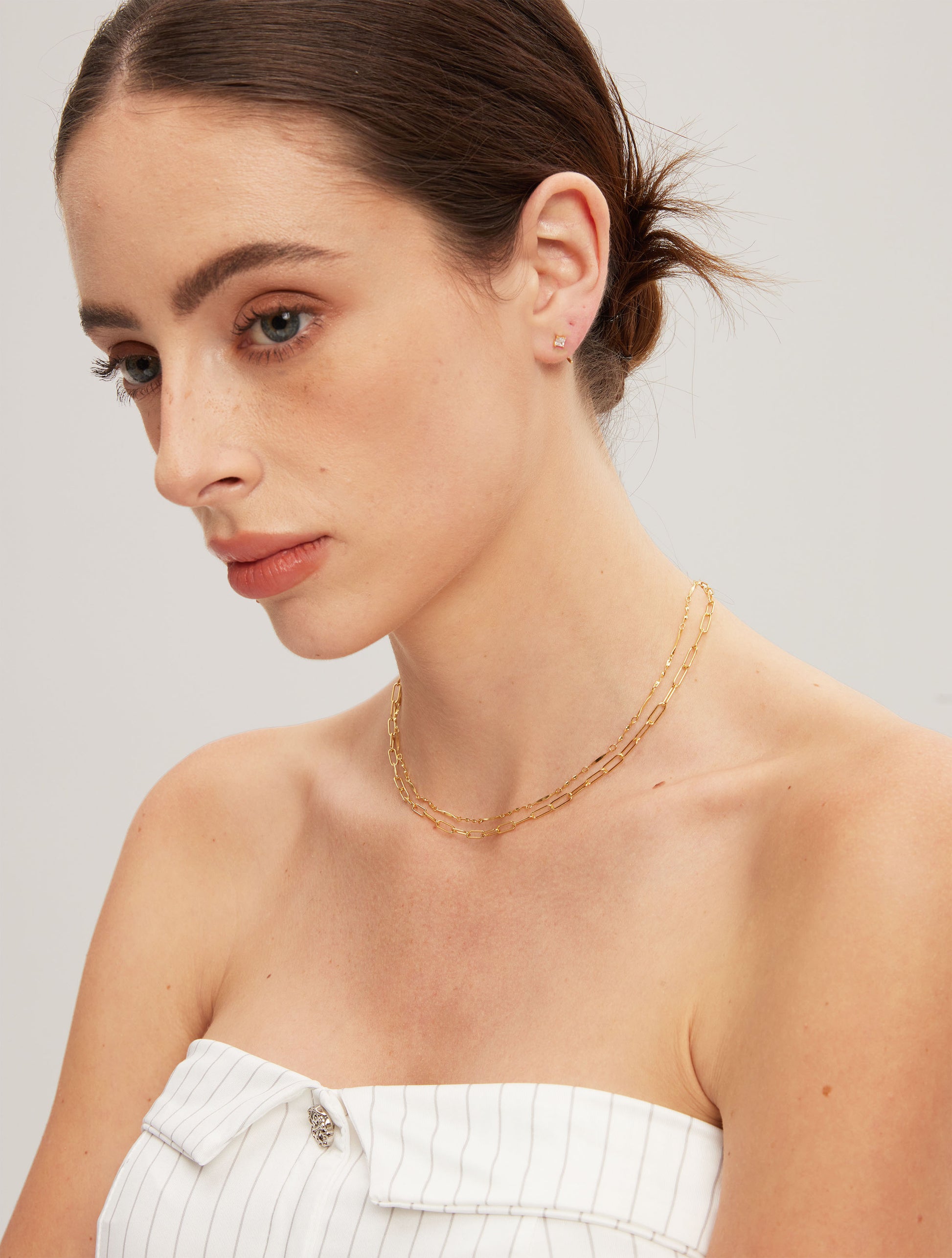 Woman wearing gold chains against a plain background