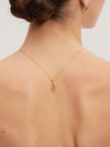 Gold necklace with a pendant on a person's neck against a neutral background