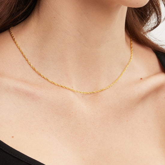 Gold necklace on a person wearing a black top