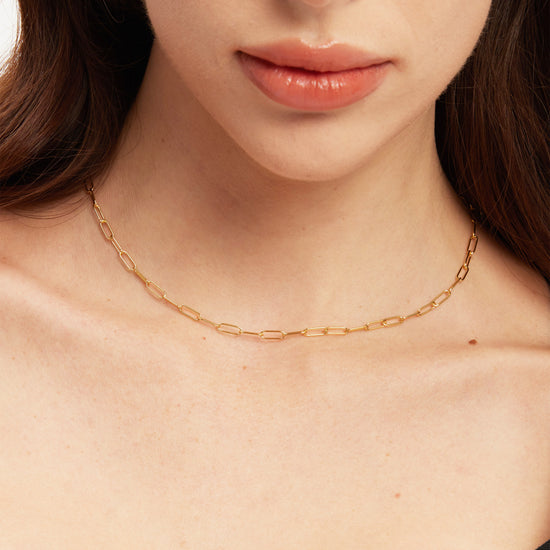Close-up of a person wearing a gold chain with a blurred background