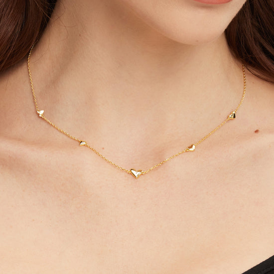 Gold necklace with heart pendants worn by a person