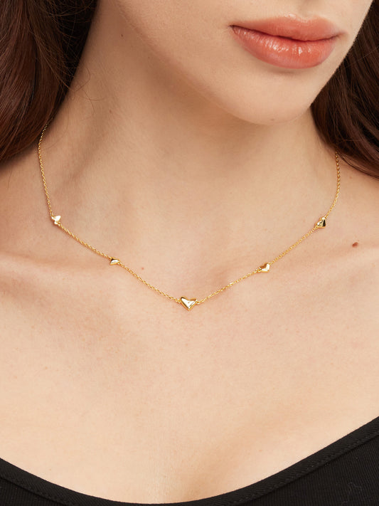 Gold necklace with heart pendants worn by a person