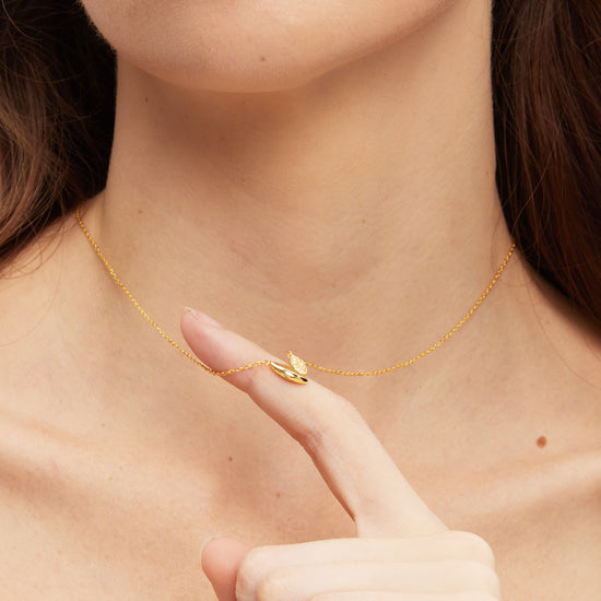 Close-up of a person wearing a gold necklace with a small pendant.
