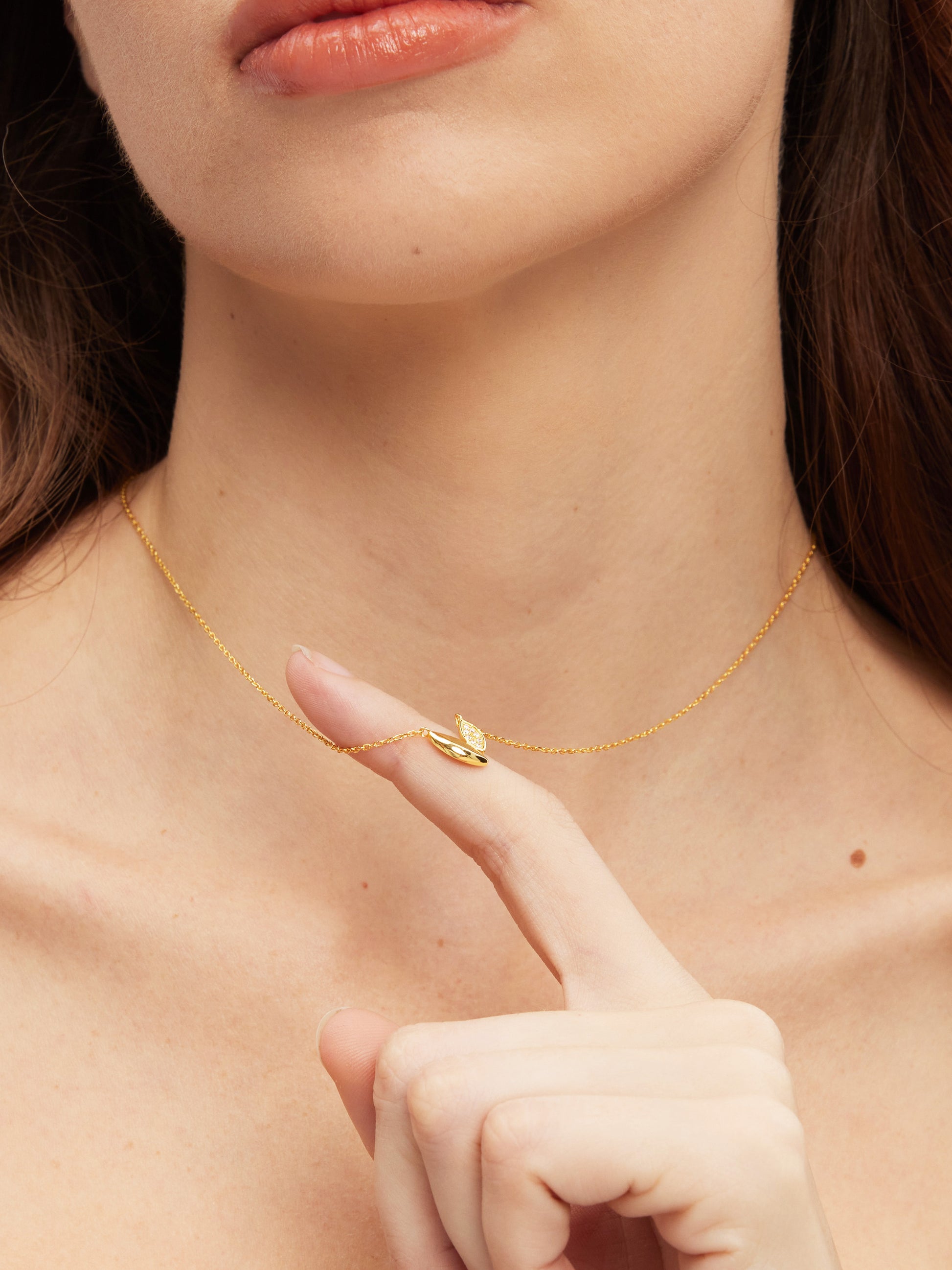 Close-up of a person wearing a gold necklace with a small pendant.