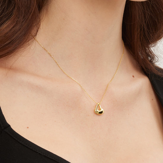 Gold necklace with a heart pendant worn by a person