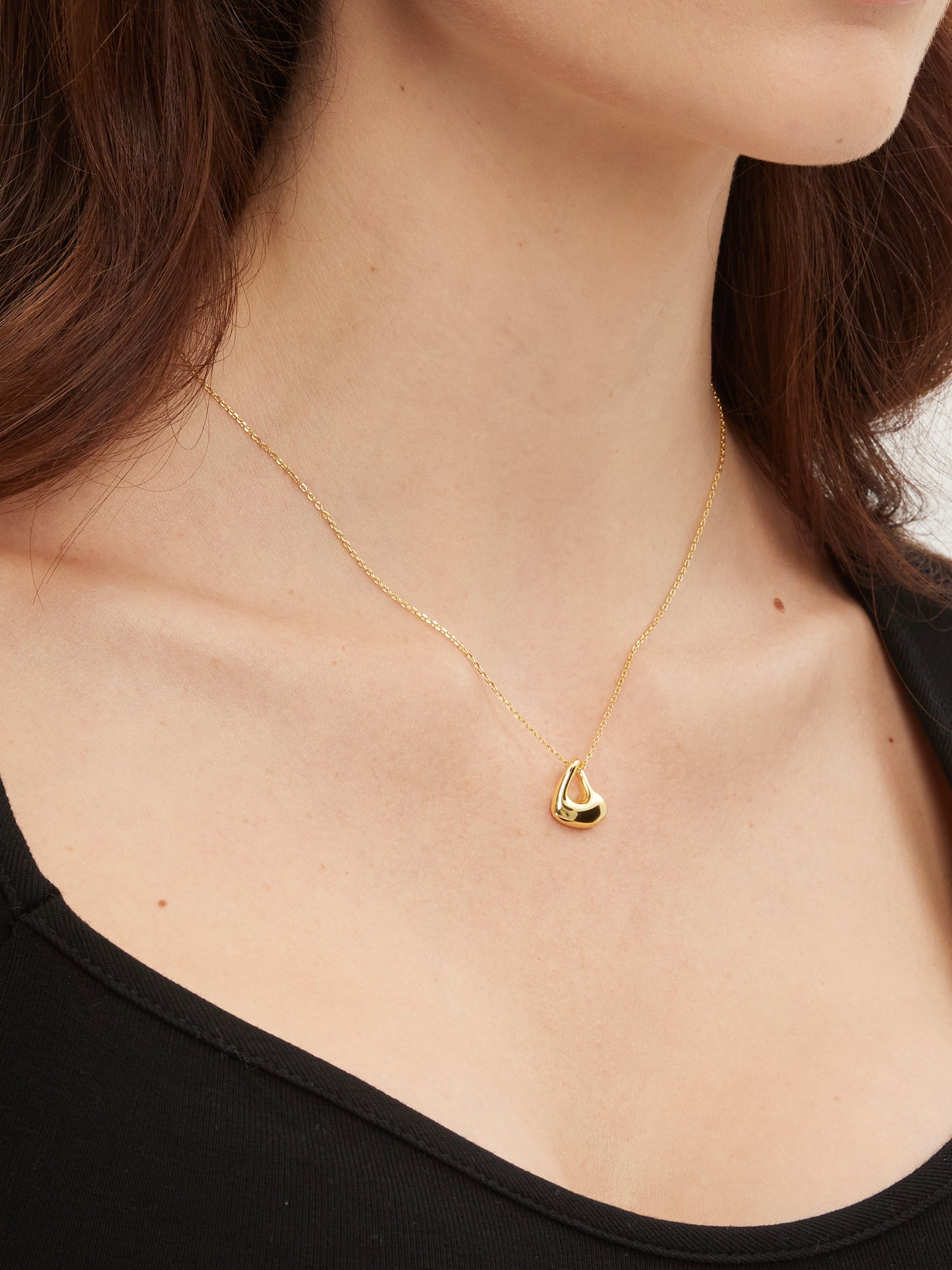 Gold necklace with a heart pendant worn by a person