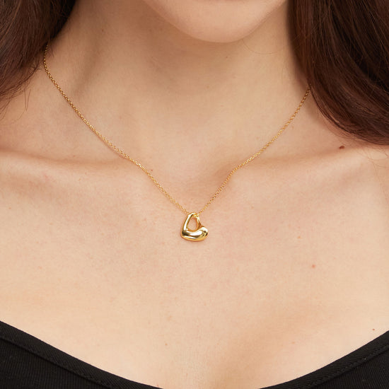 Gold necklace with a heart pendant worn by a person