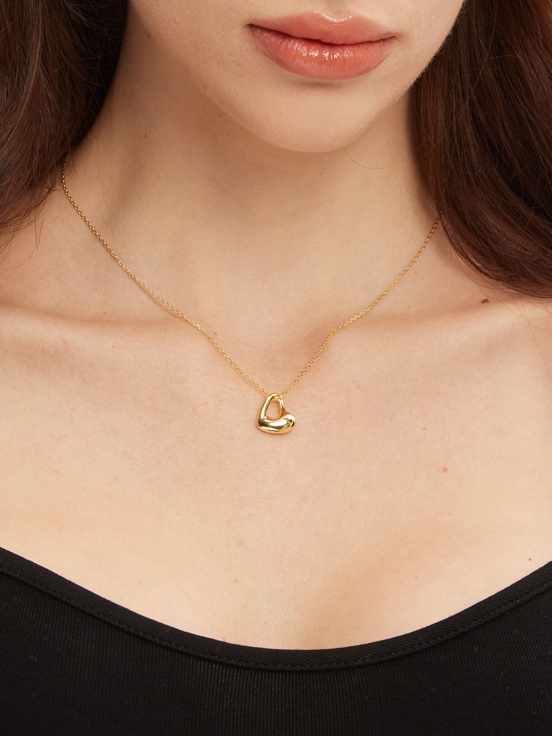 Gold necklace with a heart pendant worn by a person