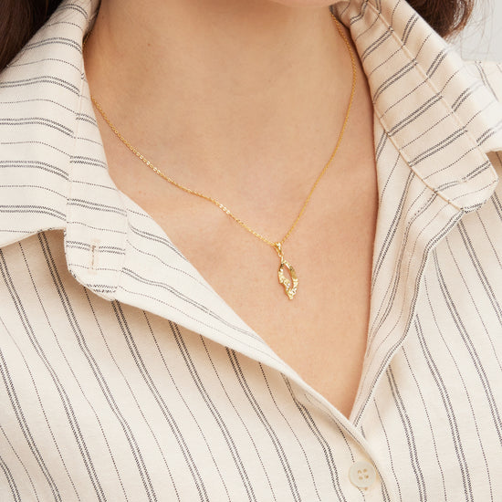 Gold necklace worn by a person with a striped shirt