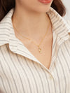 Gold necklace worn by a person with a striped shirt