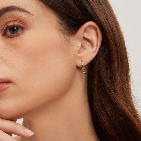 Close-up of a woman wearing a silver hoop earring with a neutral background