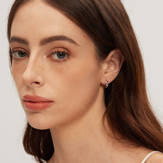 Close-up of a woman wearing a small earring on a plain background