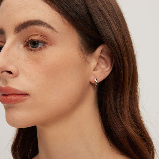 Close-up of a woman wearing a diamond earring on a plain background