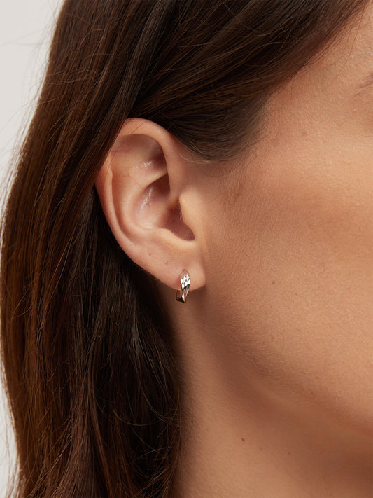 Close-up of an ear wearing a small earring with a neutral background