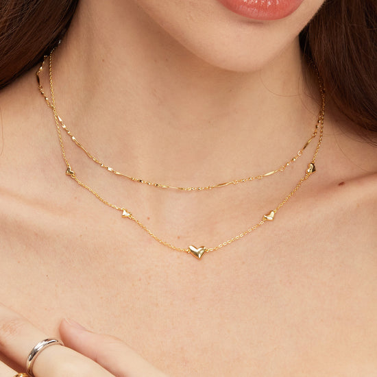 Gold necklace on a person's neck with a close-up of the jewelry.