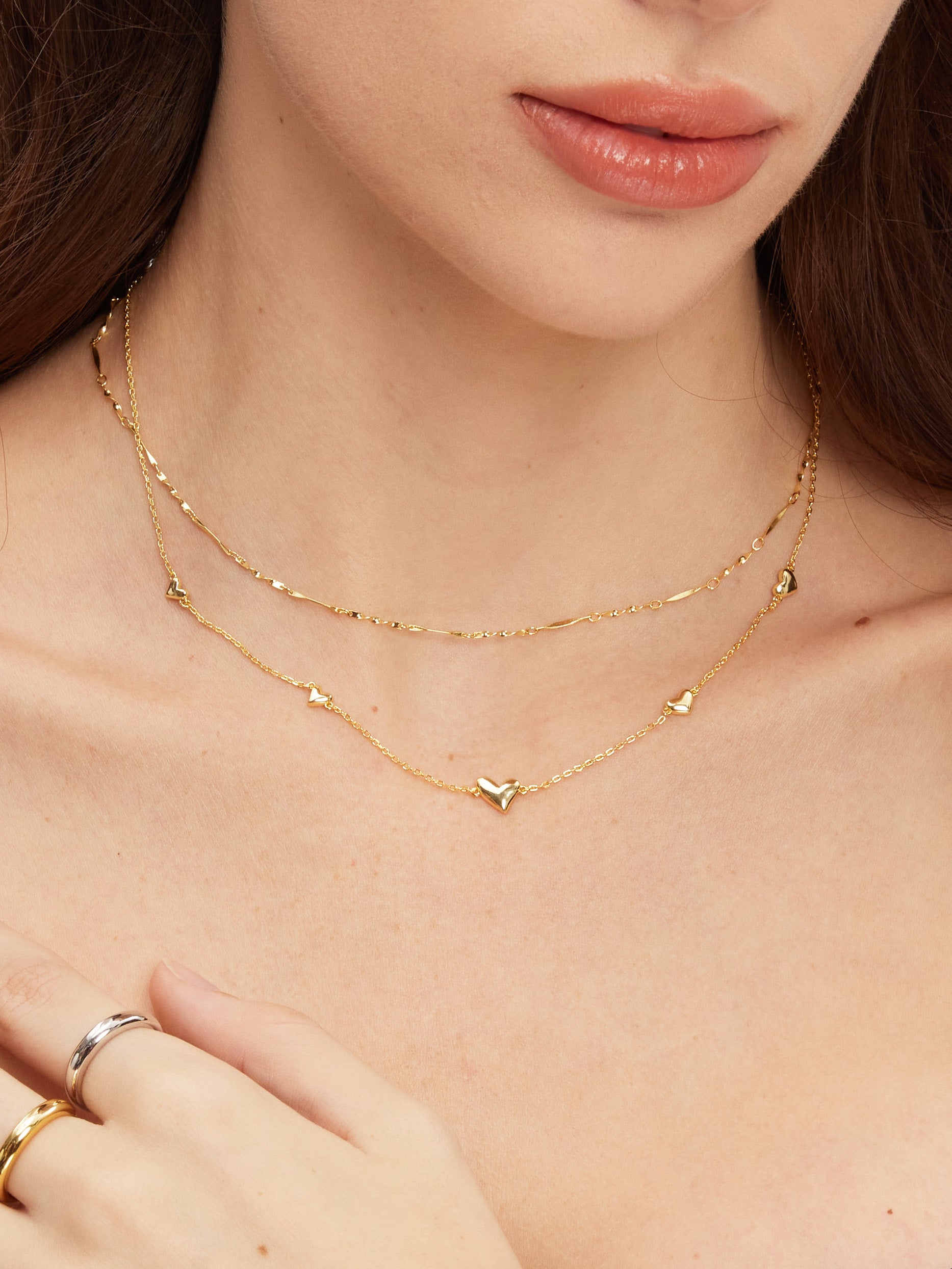 Gold necklace on a person's neck with a close-up of the jewelry.