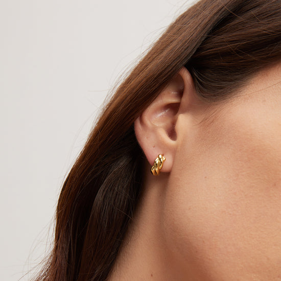 Gold earring worn by a person with a neutral background