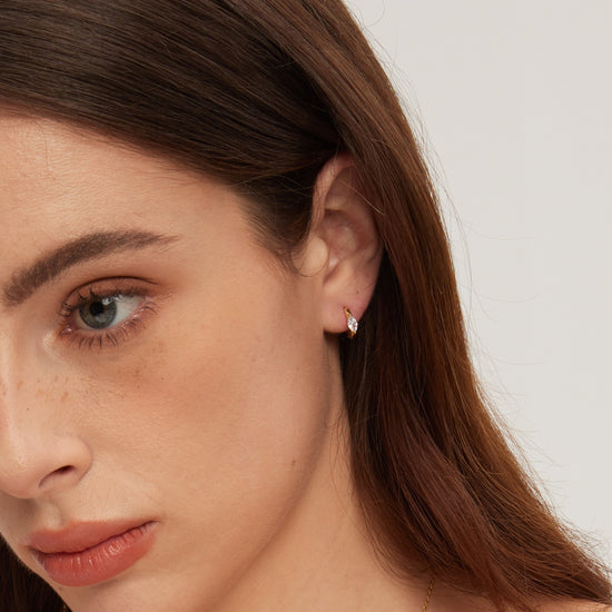 Close-up of a woman wearing a small earring on a plain background