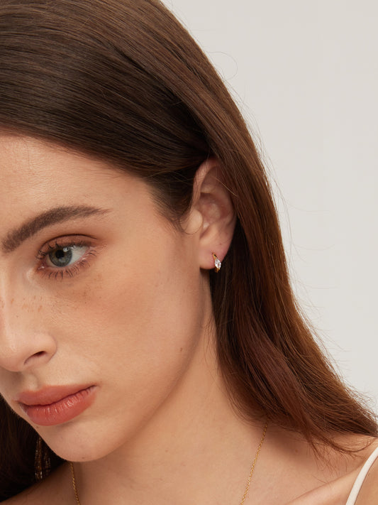 Close-up of a woman wearing a small earring on a plain background