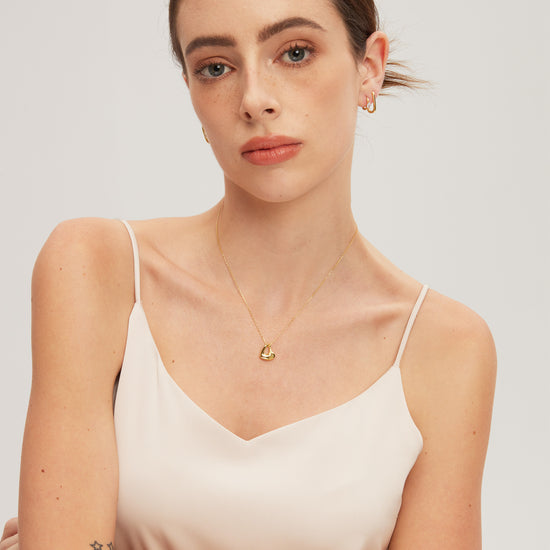 Woman wearing a gold necklace with a plain background