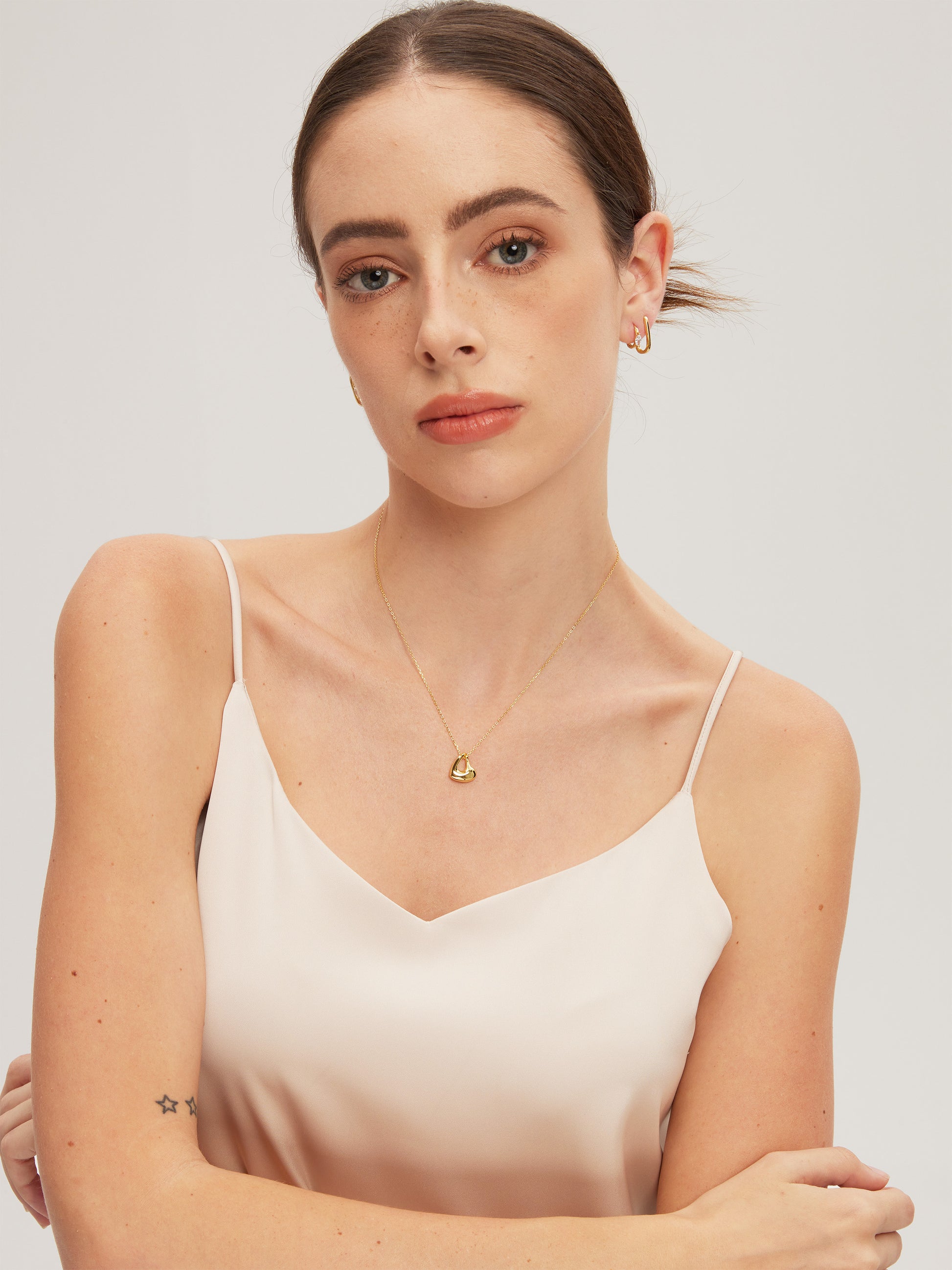 Woman wearing a gold necklace with a plain background