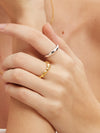 Close-up of a hand wearing mix of gold and silver rings on a neutral background