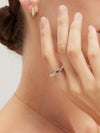 Close-up of a hand wearing a silver molten ring with a gold necklace and earring.
