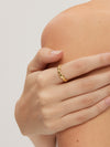 Hand wearing a gold ring on a neutral background