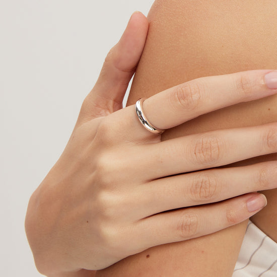 Hand wearing a silver ring on a light background