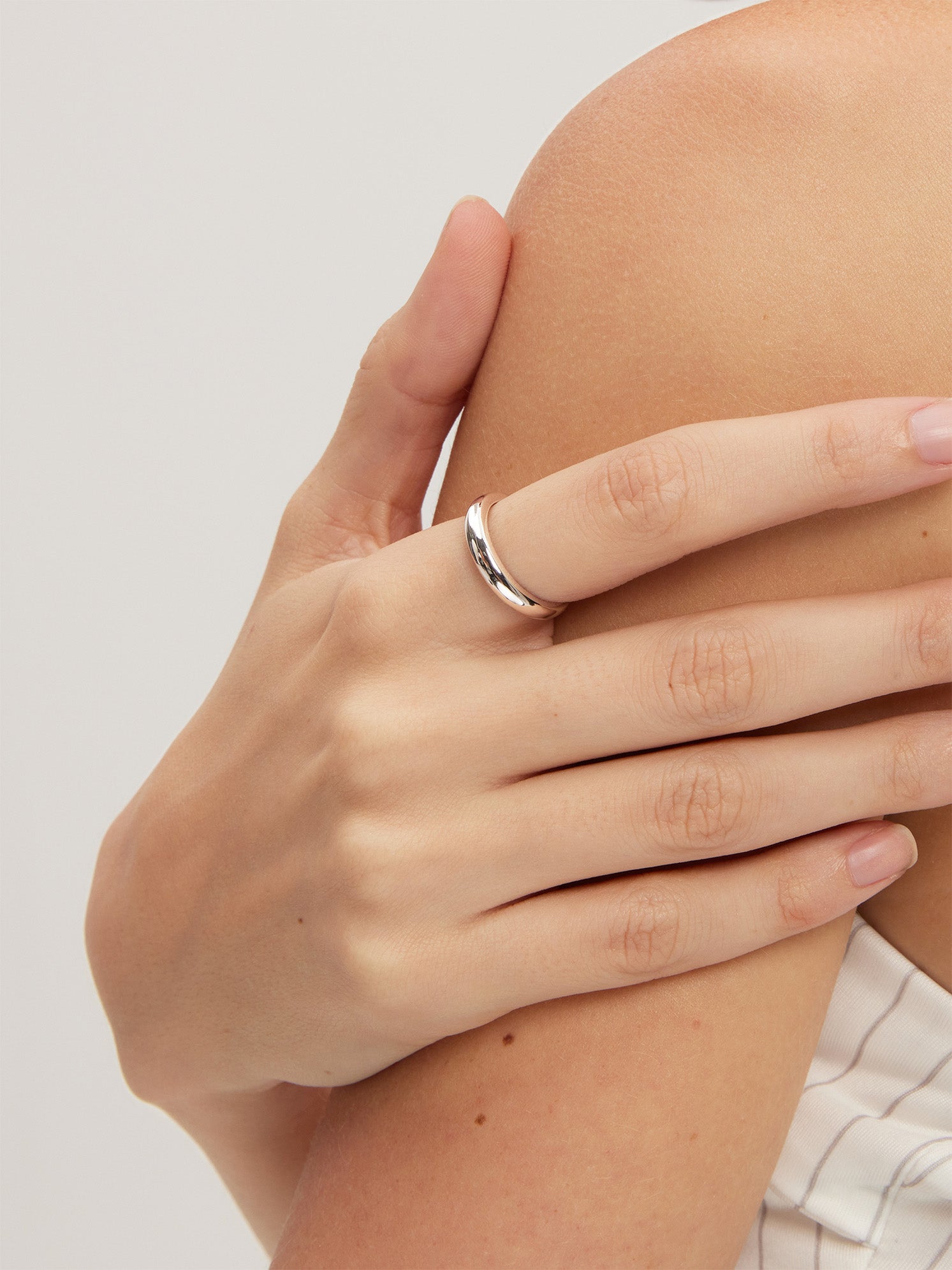 Hand wearing a silver ring on a light background