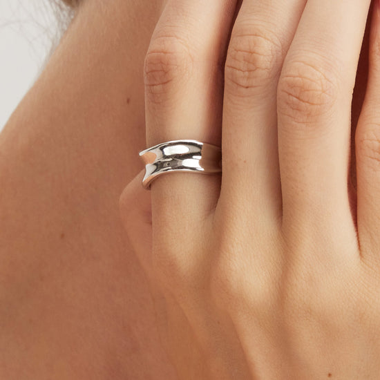 Silver ring on a person's finger with a blurred background