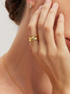 Close-up of a person wearing gold jewelry including an earring, ring, and necklace.
