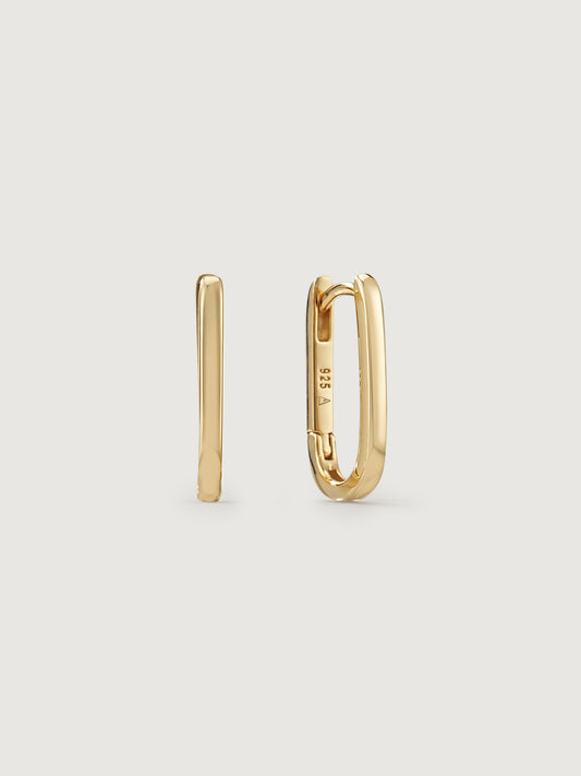 Gold hoop earrings on a light beige background