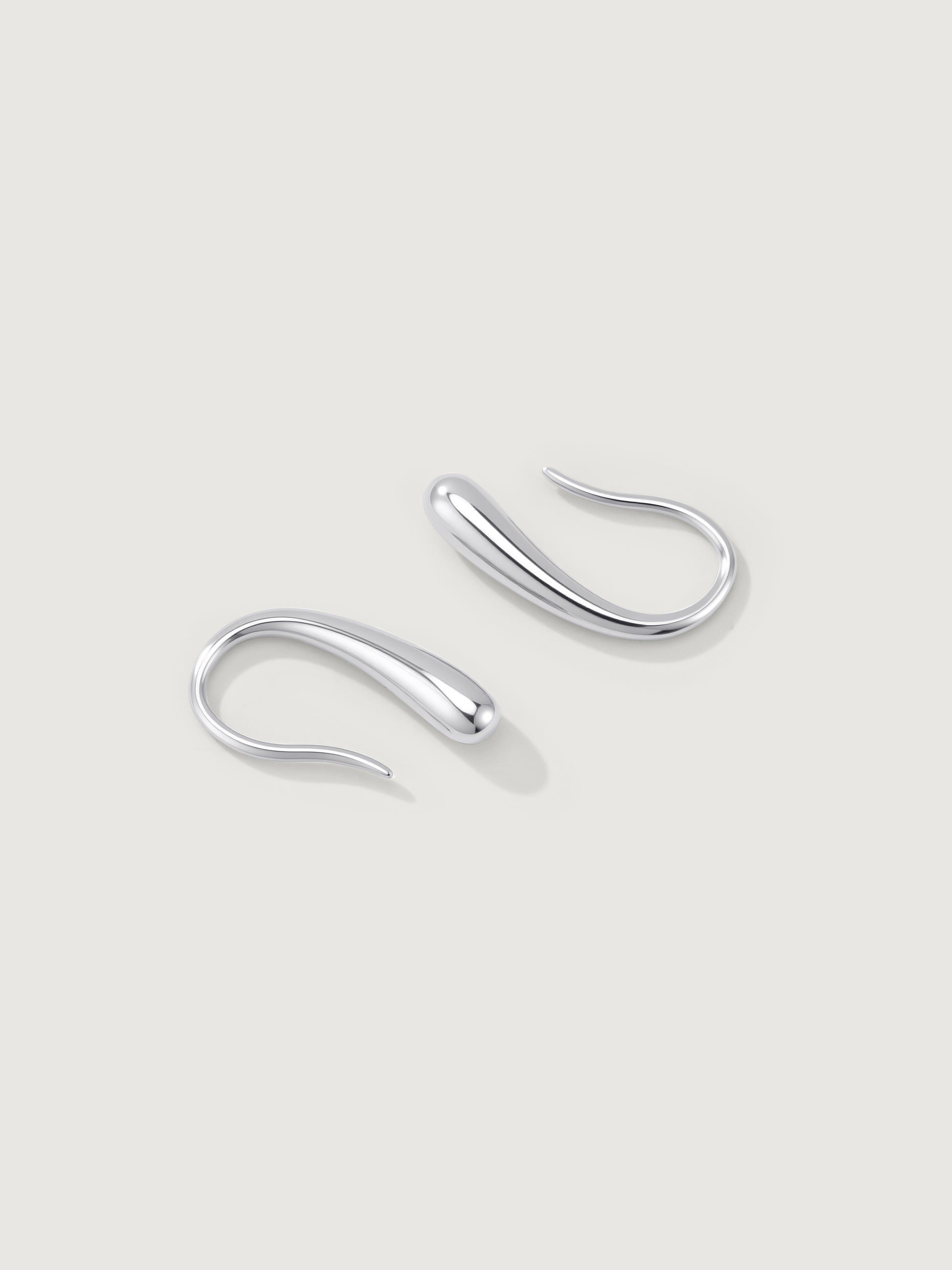 Pair of silver dune hoop earrings on a light gray background