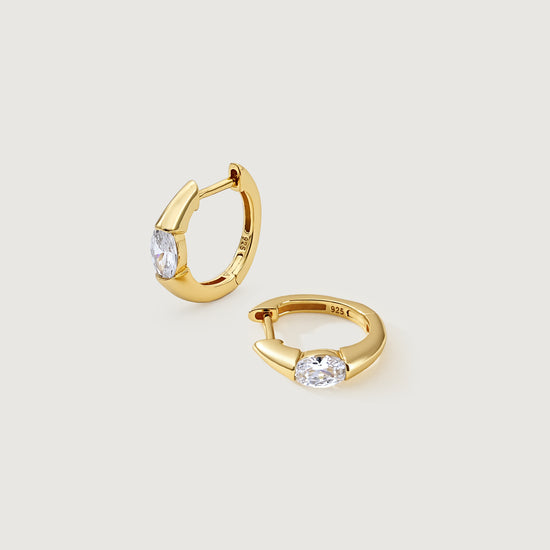 Gold hoop earrings with clear gemstones on a light gray background