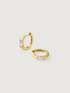 Gold hoop earrings with clear gemstones on a light gray background