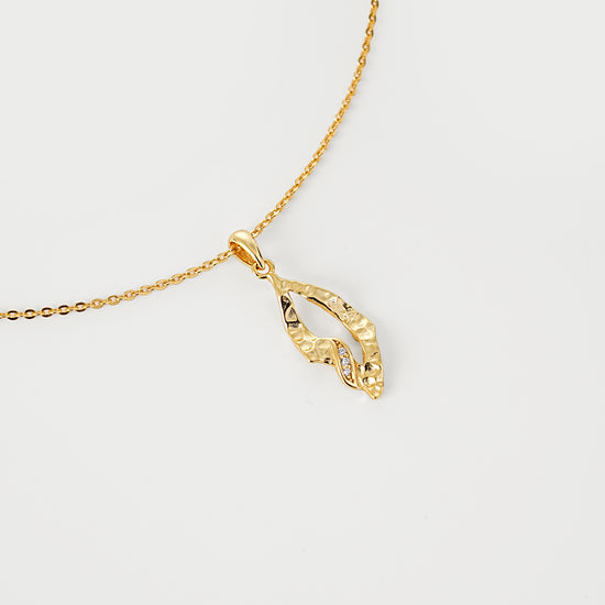 Gold necklace with a pendant on a light gray background