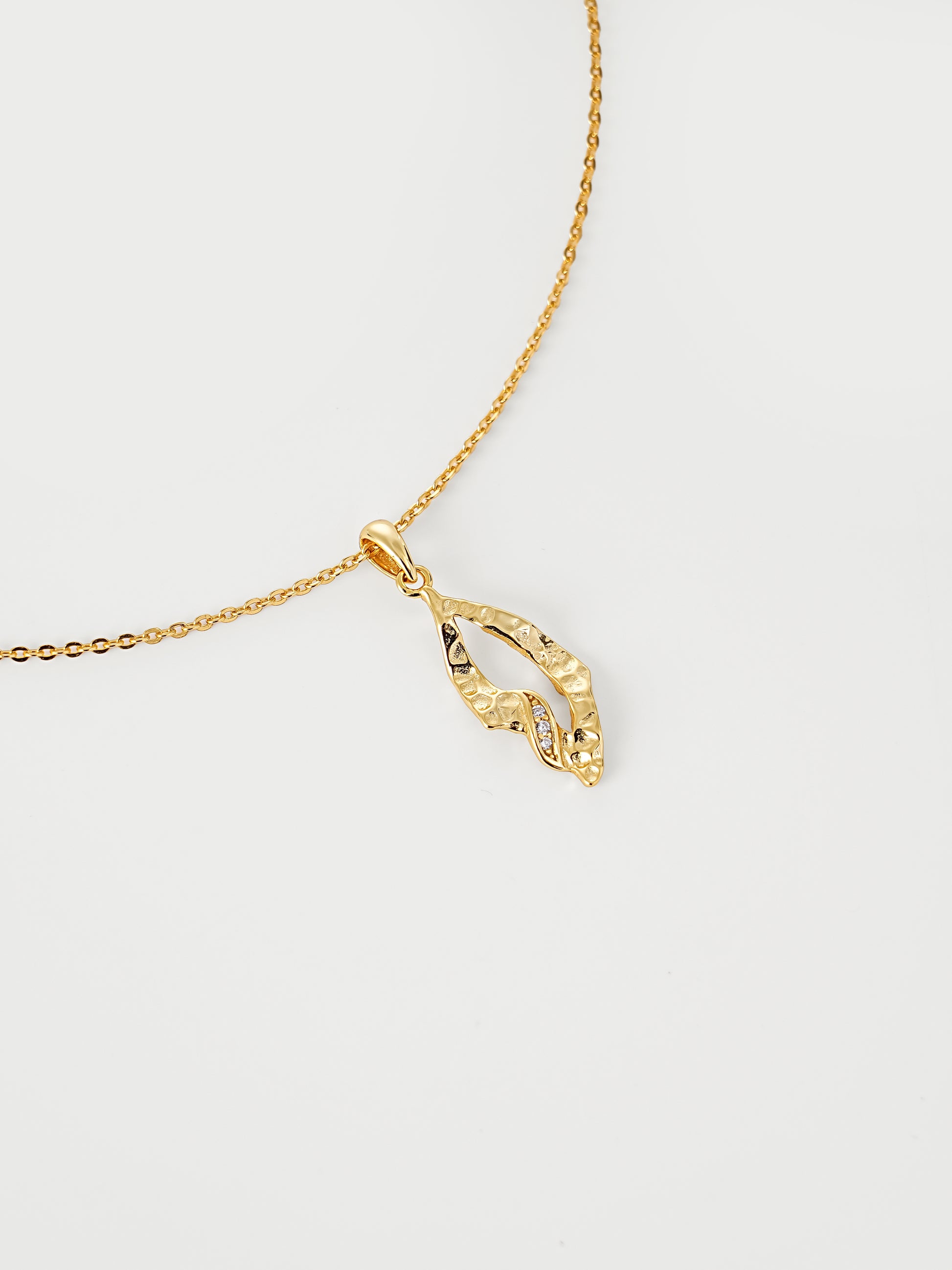 Gold necklace with a pendant on a light gray background