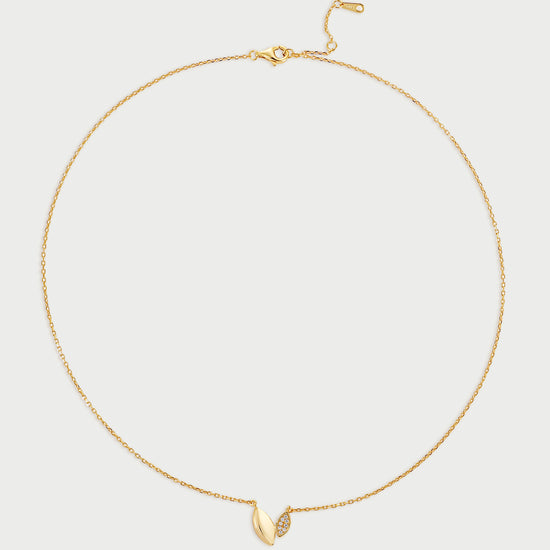 Gold necklace with a small leaf-like (also heart-like) pendant on a light gray background