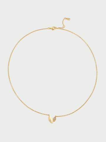 Gold necklace with a small leaf-like (also heart-like) pendant on a light gray background