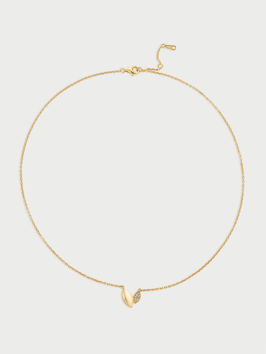Gold necklace with a small leaf-like (also heart-like) pendant on a light gray background
