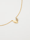 Gold necklace with a leaf-shaped pendant on a light gray background